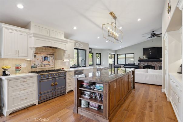 Chandelier, Fireplace, Interior, Kitchen, Living room, Pendant Lights, Recessed Lighting, Stainless Steel Appliances, Wood Texture Flooring