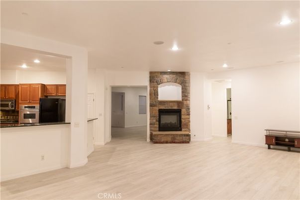 Empty room, Fireplace, Interior, Kitchen, Recessed Lighting, Stainless Steel Appliances, Stone Walls, Wood Texture Flooring