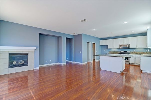 Empty room, Fireplace, Interior, Kitchen, Recessed Lighting, Stainless Steel Appliances, Wood Texture Flooring