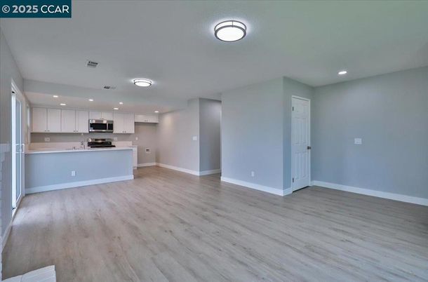 Empty room, Interior, Kitchen, Recessed Lighting, Stainless Steel Appliances, Wood Texture Flooring