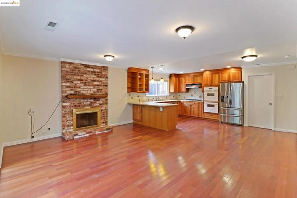 Empty room, Fireplace, Interior, Kitchen, Pendant Lights, Stainless Steel Appliances, Stone Walls, Wood Texture Flooring