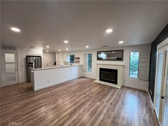 Empty room, Fireplace, Interior, Kitchen, Recessed Lighting, Stainless Steel Appliances, Wood Texture Flooring