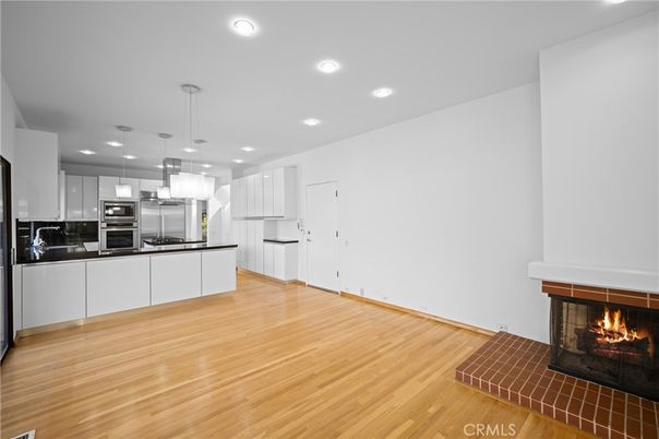 Empty room, Fireplace, Interior, Kitchen, Pendant Lights, Recessed Lighting, Stainless Steel Appliances, Wood Texture Flooring