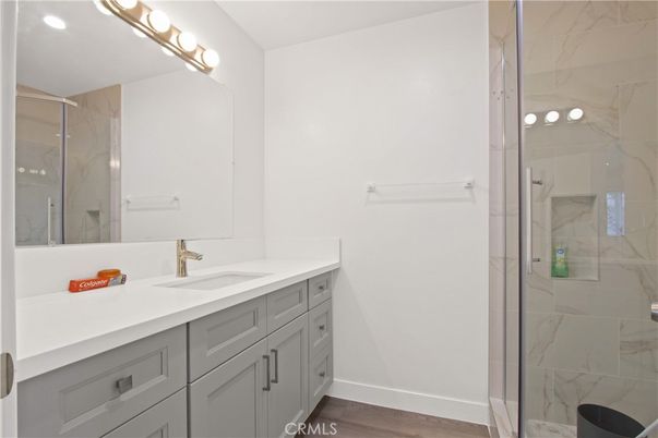 Bathroom, Dual Sink Vanities, Glass Shower, Interior, Marble Walls, Recessed Lighting, Wood Texture Flooring