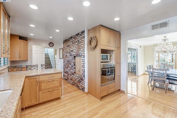 Chandelier, Dining room, Interior, Kitchen, Recessed Lighting, Stainless Steel Appliances, Stone Walls, Wood Texture Flooring