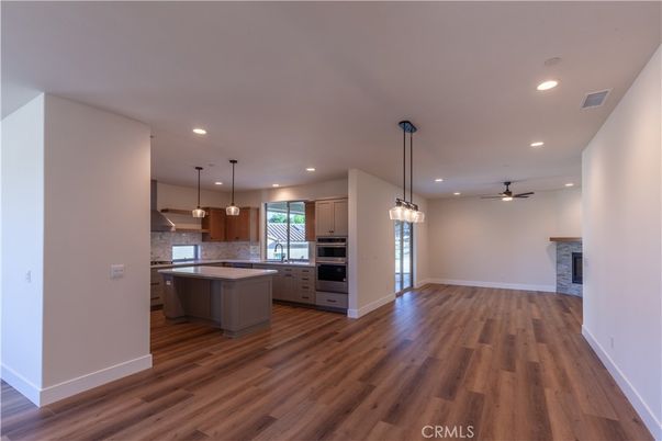 Empty room, Fireplace, Interior, Kitchen, Pendant Lights, Recessed Lighting, Stainless Steel Appliances, Wood Texture Flooring