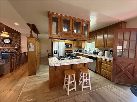 Fireplace, Interior, Kitchen, Pendant Lights, Recessed Lighting, Stainless Steel Appliances, Stone Walls, Tile Countertops, Wood Texture Flooring