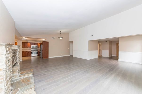 Empty room, Fireplace, Interior, Kitchen, Pendant Lights, Stainless Steel Appliances, Wood Texture Flooring