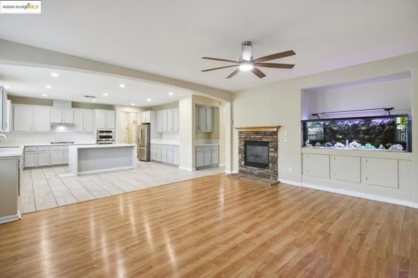 Empty room, Fireplace, Interior, Kitchen, Recessed Lighting, Stainless Steel Appliances, Wood Texture Flooring