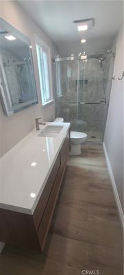 Bathroom, Dual Sink Vanities, Glass Shower, Interior, Marble Walls, Recessed Lighting, Wood Texture Flooring