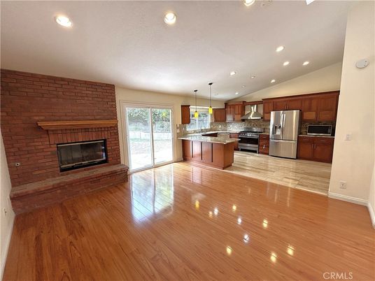 Empty room, Fireplace, Interior, Kitchen, Pendant Lights, Recessed Lighting, Stainless Steel Appliances, Stone Walls, Wood Texture Flooring