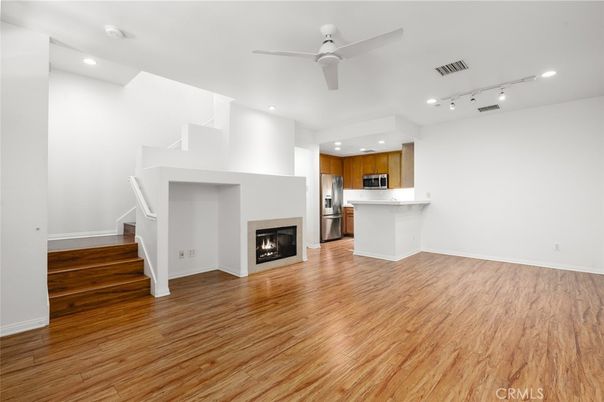 Empty room, Fireplace, Interior, Kitchen, Recessed Lighting, Stainless Steel Appliances, Wood Texture Flooring