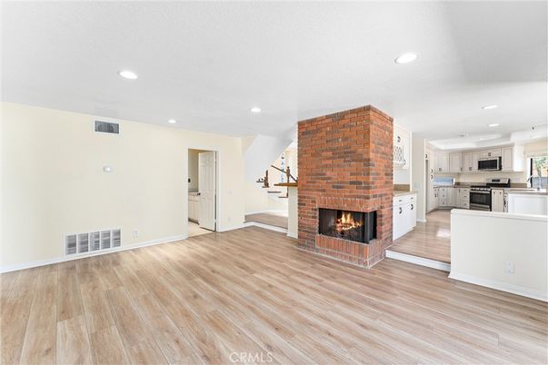 Empty room, Fireplace, Interior, Kitchen, Recessed Lighting, Stainless Steel Appliances, Stone Walls, Wood Texture Flooring