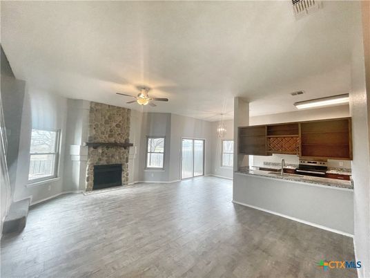 Empty room, Fireplace, Interior, Kitchen, Pendant Lights, Stainless Steel Appliances, Stone Walls, Wood Texture Flooring