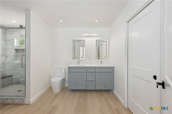 Bathroom, Dual Sink Vanities, Glass Shower, Interior, Marble Walls, Recessed Lighting, Wood Texture Flooring