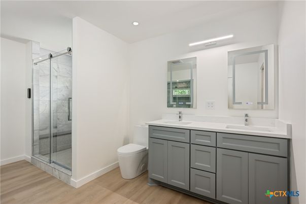 Bathroom, Dual Sink Vanities, Glass Shower, Interior, Marble Walls, Recessed Lighting, Wood Texture Flooring