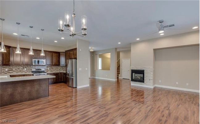 Empty room, Fireplace, Interior, Kitchen, Pendant Lights, Recessed Lighting, Stainless Steel Appliances, Wood Texture Flooring