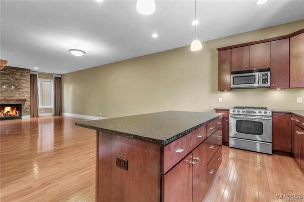 Fireplace, Interior, Kitchen, Pendant Lights, Recessed Lighting, Stainless Steel Appliances, Stone Walls, Wood Texture Flooring