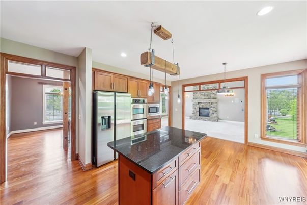 Empty room, Fireplace, Interior, Kitchen, Pendant Lights, Recessed Lighting, Stainless Steel Appliances, Wood Texture Flooring