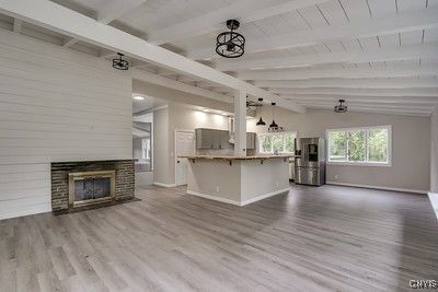 Empty room, Fireplace, Interior, Kitchen, Pendant Lights, Stainless Steel Appliances, Wood Texture Flooring