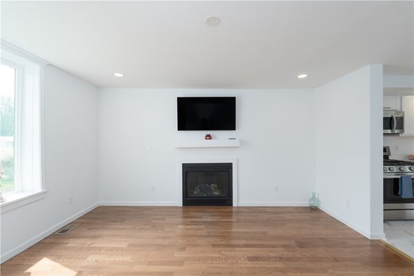 Empty room, Fireplace, Interior, Kitchen, Recessed Lighting, Stainless Steel Appliances, Wood Texture Flooring
