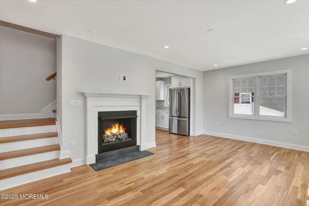 Empty room, Fireplace, Interior, Kitchen, Recessed Lighting, Stainless Steel Appliances, Wood Texture Flooring