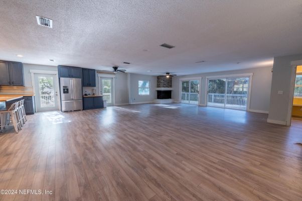 Empty room, Fireplace, Interior, Kitchen, Recessed Lighting, Stainless Steel Appliances, Wood Texture Flooring