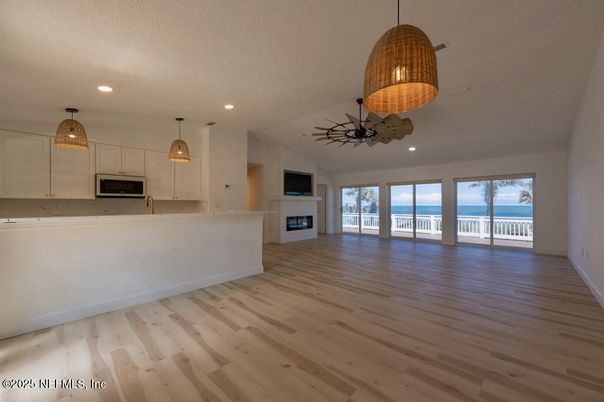 Empty room, Fireplace, Interior, Kitchen, Pendant Lights, Recessed Lighting, Stainless Steel Appliances, Wood Texture Flooring