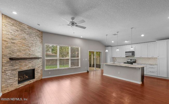 Empty room, Fireplace, Interior, Kitchen, Pendant Lights, Recessed Lighting, Stainless Steel Appliances, Stone Walls, Wood Texture Flooring