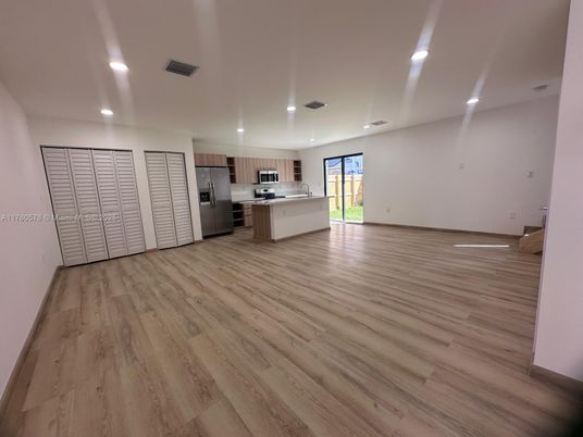 Empty room, Interior, Kitchen, Recessed Lighting, Stainless Steel Appliances, Wood Texture Flooring