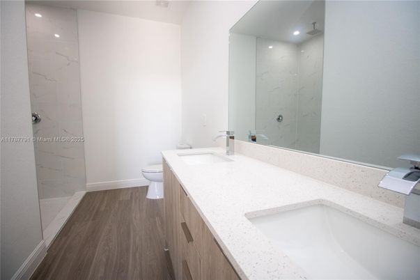 Bathroom, Dual Sink Vanities, Glass Shower, Interior, Marble Walls, Recessed Lighting, Wood Texture Flooring
