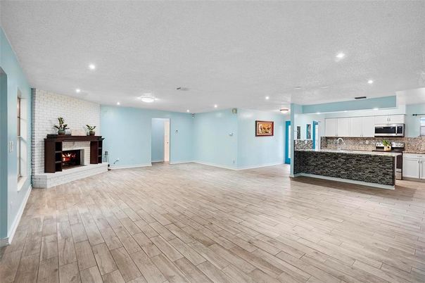 Empty room, Fireplace, Interior, Kitchen, Recessed Lighting, Stainless Steel Appliances, Stone Walls, Wood Texture Flooring