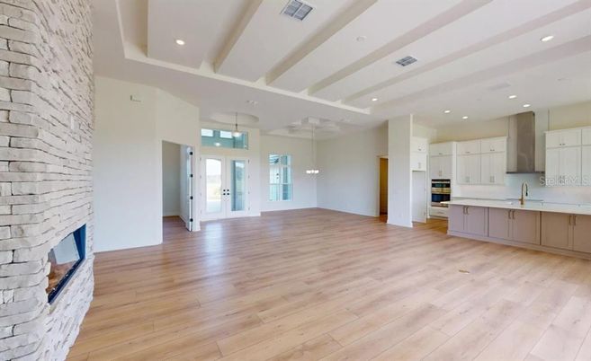Empty room, Fireplace, Interior, Kitchen, Pendant Lights, Recessed Lighting, Stainless Steel Appliances, Stone Walls, Wood Texture Flooring