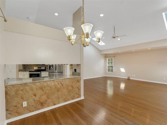 Chandelier, Empty room, Fireplace, Interior, Kitchen, Recessed Lighting, Stainless Steel Appliances, Wood Texture Flooring