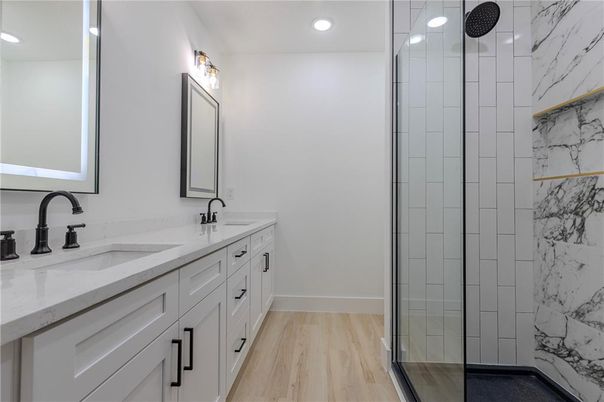 Bathroom, Dual Sink Vanities, Glass Shower, Interior, Marble Walls, Recessed Lighting, Wood Texture Flooring