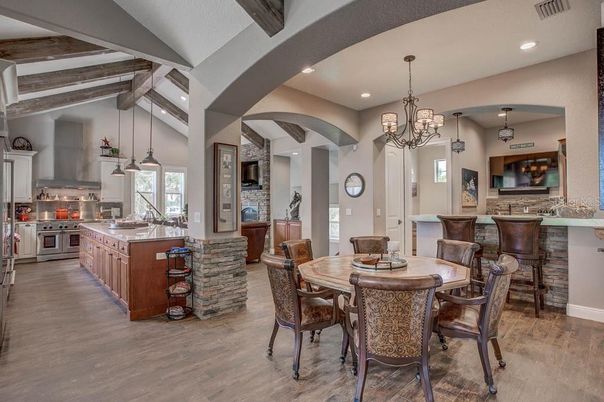 Chandelier, Dining room, Fireplace, Interior, Kitchen, Pendant Lights, Recessed Lighting, Stainless Steel Appliances, Stone Walls, Wooden Beams, Wood Texture Flooring