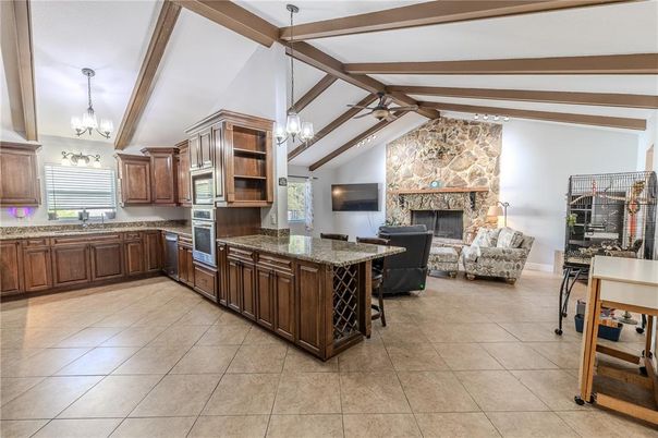 Chandelier, Fireplace, Interior, Kitchen, Living room, Pendant Lights, Stainless Steel Appliances, Stone Walls, Wooden Beams