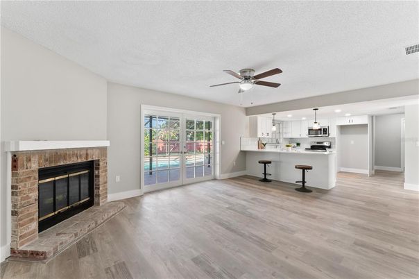 Empty room, Fireplace, Interior, Kitchen, Pendant Lights, Stainless Steel Appliances, Wood Texture Flooring