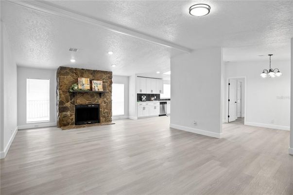 Empty room, Fireplace, Interior, Kitchen, Pendant Lights, Recessed Lighting, Stainless Steel Appliances, Stone Walls, Wood Texture Flooring