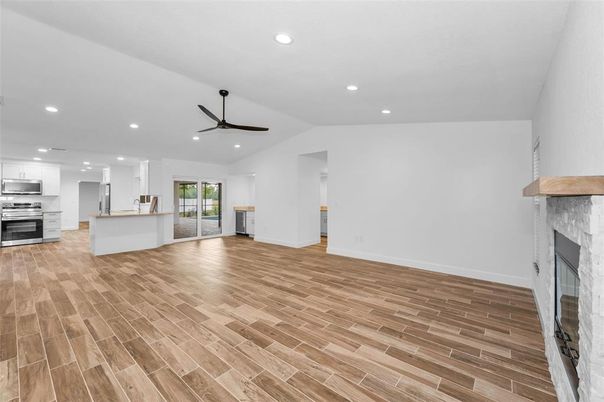 Empty room, Fireplace, Interior, Kitchen, Recessed Lighting, Stainless Steel Appliances, Wood Texture Flooring