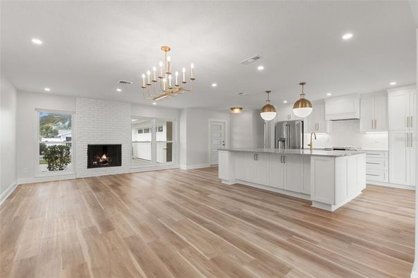 Empty room, Fireplace, Interior, Kitchen, Pendant Lights, Recessed Lighting, Stainless Steel Appliances, Wood Texture Flooring
