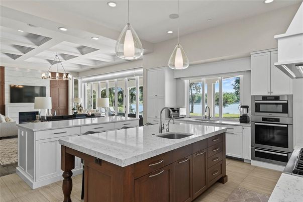 Chandelier, Fireplace, Interior, Kitchen, Living room, Pendant Lights, Recessed Lighting, Stainless Steel Appliances, Water, Wood Texture Flooring