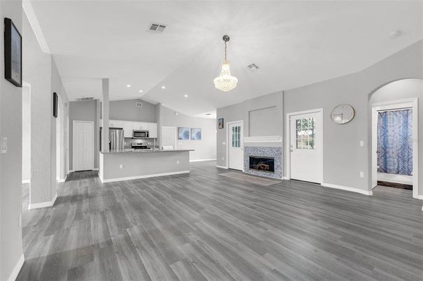 Chandelier, Empty room, Fireplace, Interior, Kitchen, Recessed Lighting, Stainless Steel Appliances, Wood Texture Flooring