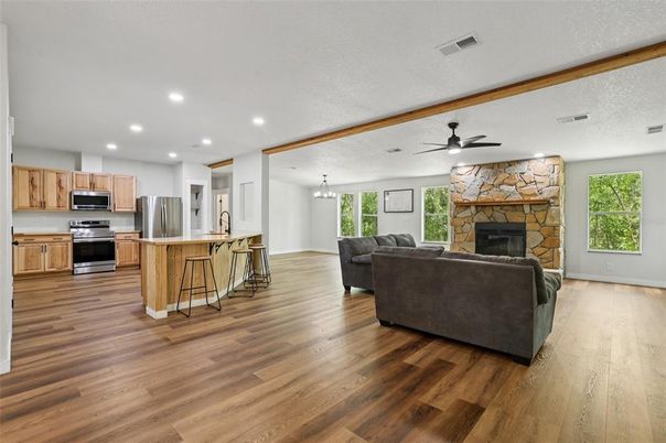 Chandelier, Fireplace, Interior, Kitchen, Living room, Pendant Lights, Recessed Lighting, Stainless Steel Appliances, Stone Walls, Wood Texture Flooring
