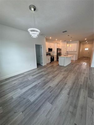 Chandelier, Empty room, Interior, Kitchen, Pendant Lights, Recessed Lighting, Stainless Steel Appliances, Wood Texture Flooring