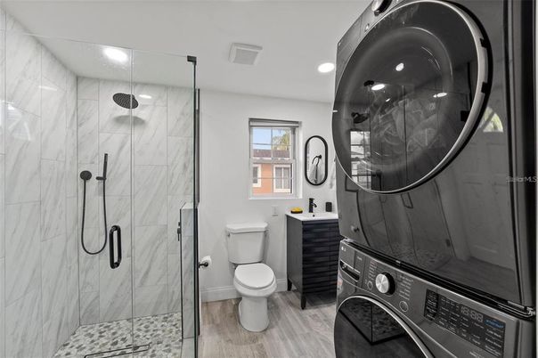 Bathroom, Glass Shower, Interior, Marble Walls, Recessed Lighting, Washer, Wood Texture Flooring