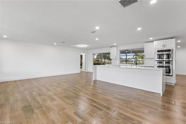 Empty room, Interior, Kitchen, Recessed Lighting, Stainless Steel Appliances, Wood Texture Flooring