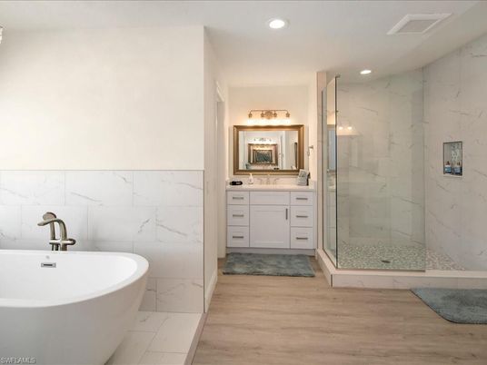 Bathroom, Dual Sink Vanities, Free Standing Baths, Glass Shower, Interior, Marble Walls, Recessed Lighting, Wood Texture Flooring