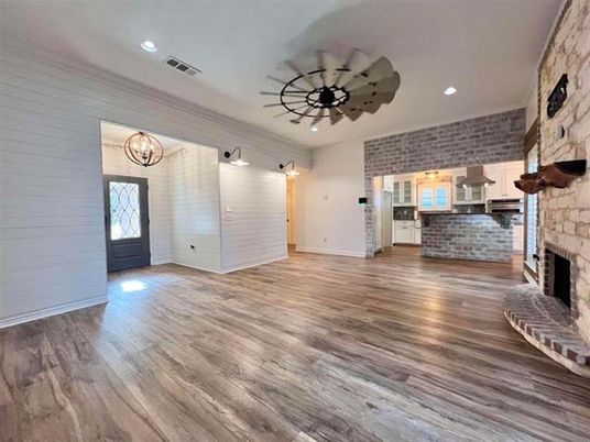Chandelier, Empty room, Fireplace, Interior, Kitchen, Recessed Lighting, Stainless Steel Appliances, Stone Walls, Wood Texture Flooring