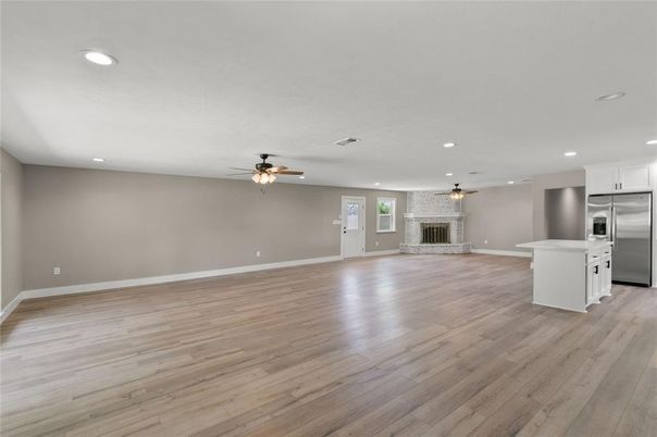 Empty room, Fireplace, Interior, Kitchen, Recessed Lighting, Stainless Steel Appliances, Wood Texture Flooring